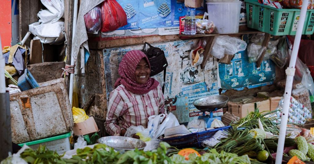 Wanita tersenyum menjual produk segar di pasar di Pontianak, Indonesia.