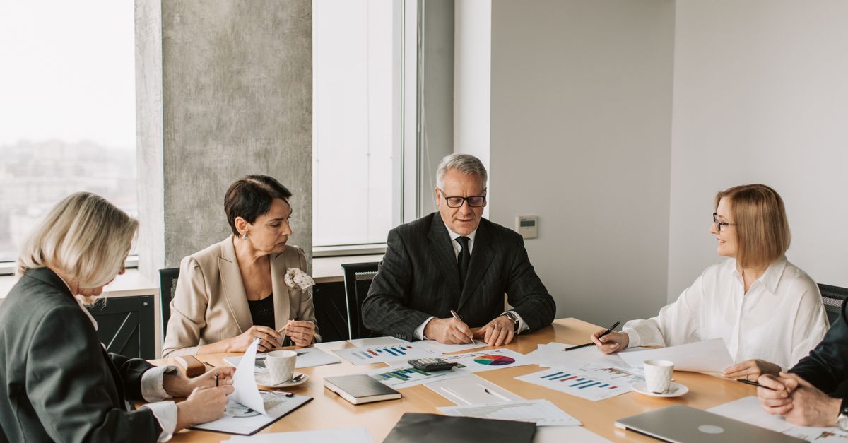 Sekelompok profesional mendiskusikan dokumen bisnis selama rapat di lingkungan kantor modern.