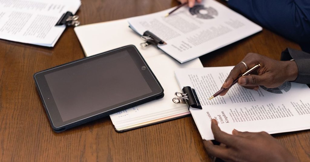 Pertemuan bisnis dengan tablet dan dokumen yang menampilkan integrasi digital dalam suasana profesional.