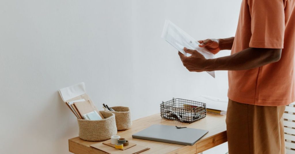 Seorang pria dengan pakaian santai mengatur kertas di meja kantor modern.