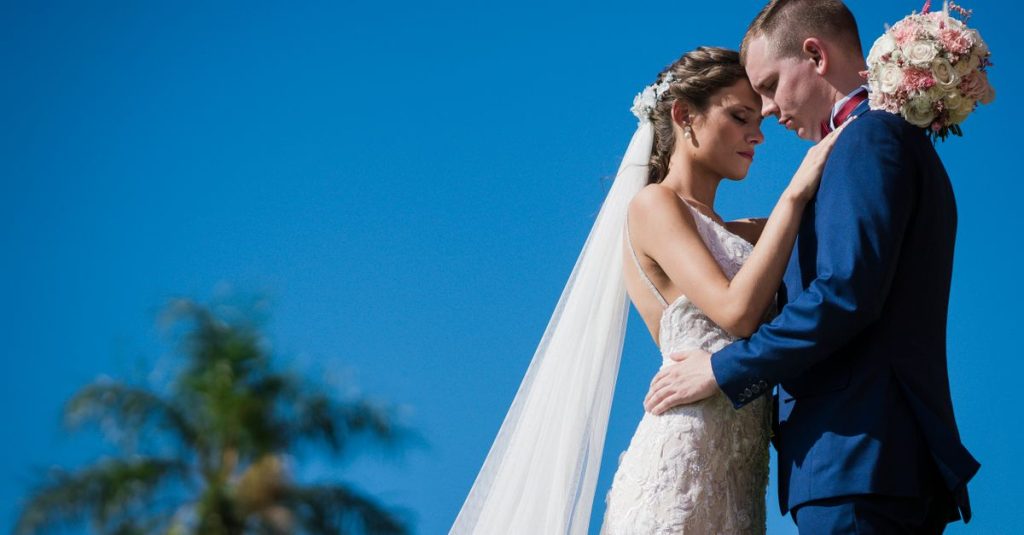 Pengantin berbagi momen lembut di luar ruangan di bawah langit biru di Paraguay.