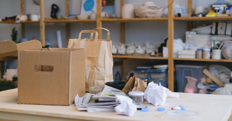 Kardus dan tas kertas di meja dalam ruang kerja berantakan dengan rak. Ideal untuk konsep pengemasan.
