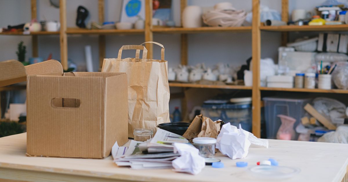 Kardus dan tas kertas di meja dalam ruang kerja berantakan dengan rak. Ideal untuk konsep pengemasan.