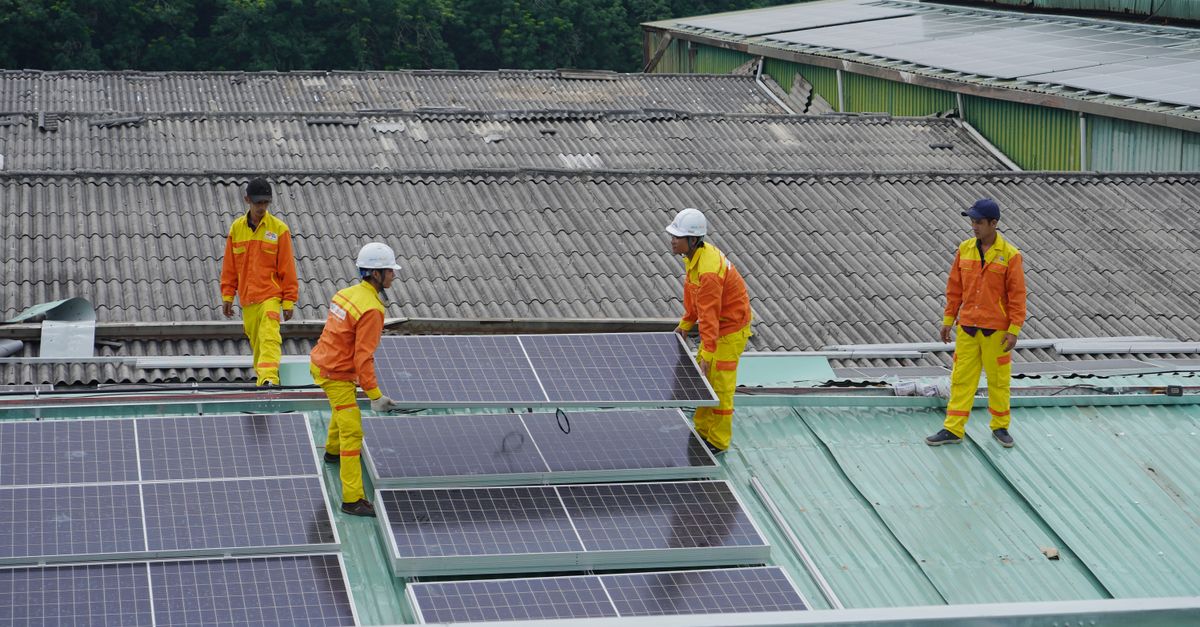 Pekerja memasang panel surya di atap untuk solusi energi berkelanjutan.