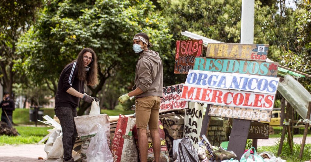 Dua relawan membersihkan taman di Bogotá, Kolombia, mempromosikan keberlanjutan lingkungan.