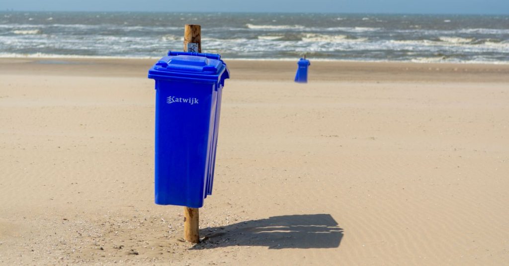 Pantai yang terang dengan tempat sampah biru di tepi laut di Katwijk aan Zee, Belanda.