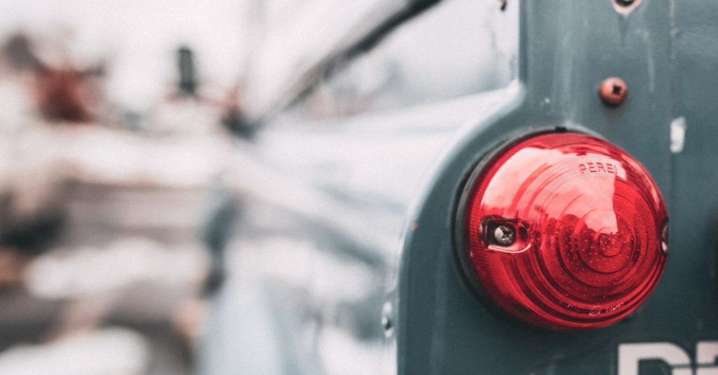 Detail dari lampu belakang merah kendaraan vintage yang menampilkan elemen desain klasik.