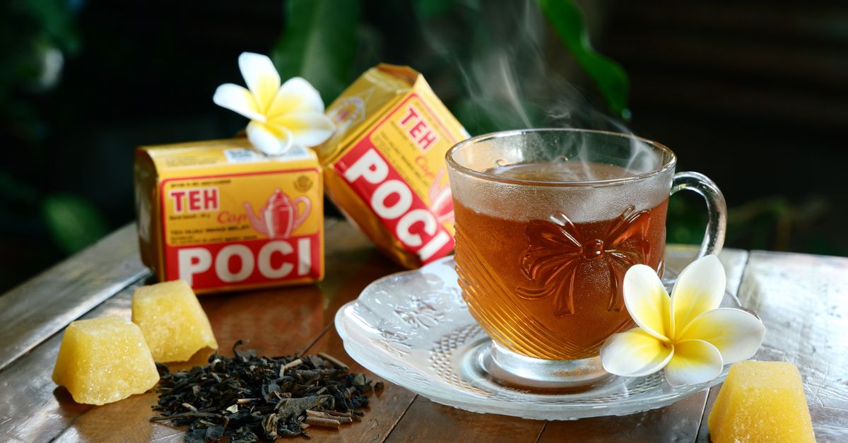 Cangkir hangat teh herbal aromatik dengan bunga plumeria dan penyajian tradisional.