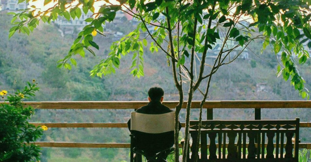 Seorang pria menikmati kesendirian di balkon di tengah alam di Dalat, Vietnam.