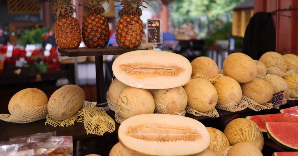 Melon segar dan nanas dipajang di pasar luar ruangan yang meriah.
