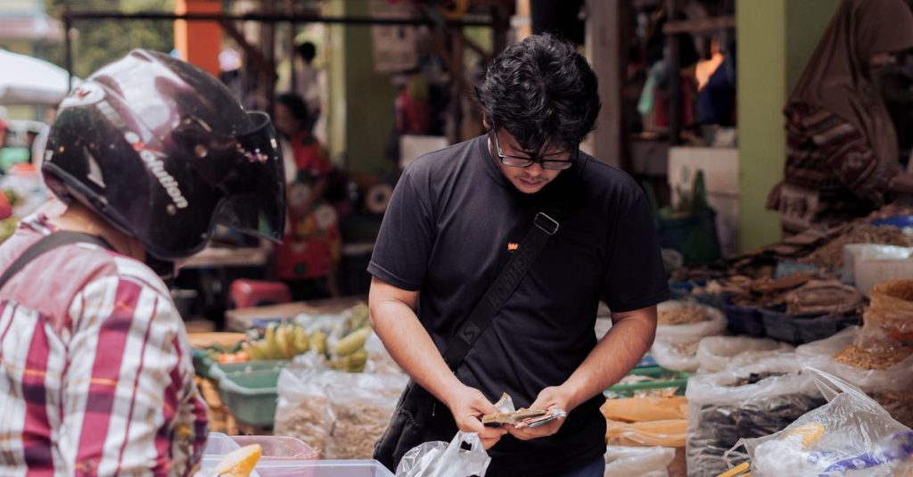 Seorang pria menghitung uang di pasar jalanan yang ramai di Pontianak, Indonesia.