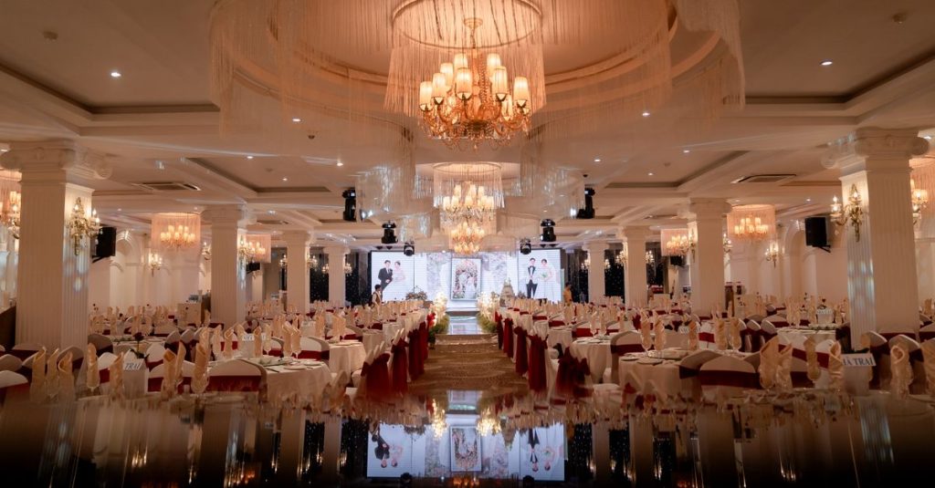 Balai mewah yang disusun dengan indah untuk acara malam yang megah, dengan chandelier menerangi dekorasi.