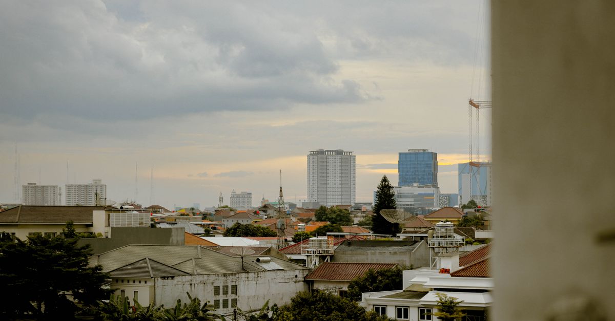 Pemandangan cakrawala Jakarta Barat yang menenangkan saat matahari terbenam, menyoroti arsitektur perkotaan.