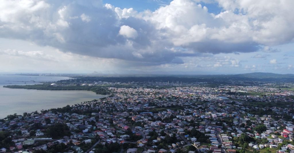 Pemandangan kota pesisir yang luas dari ketinggian dengan awan yang dramatis dan lanskap yang indah.
