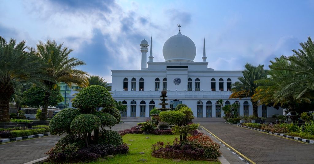 Masjid putih yang menakjubkan dengan lanskap taman di Jakarta, memamerkan arsitektur yang indah di bawah langit biru cerah.