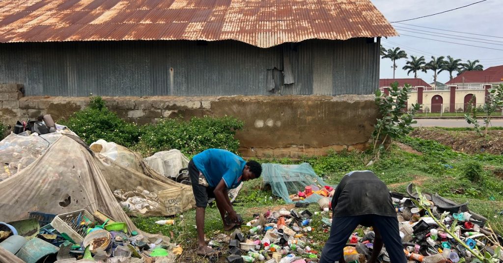 Dua pria membersihkan sampah plastik di dekat gudang, upaya lingkungan.