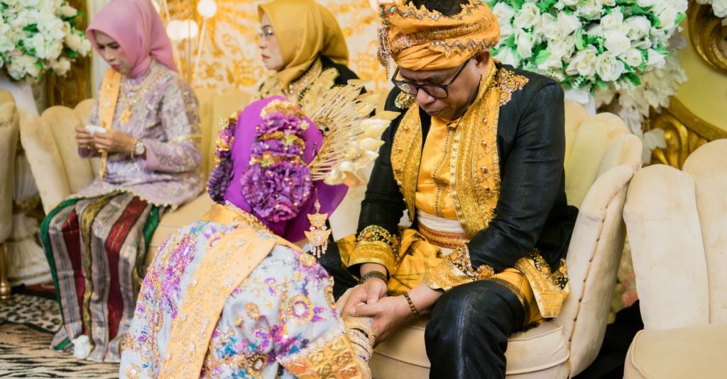 Upacara pernikahan tradisional yang meriah berlangsung di dalam ruangan di Kendari, Indonesia.