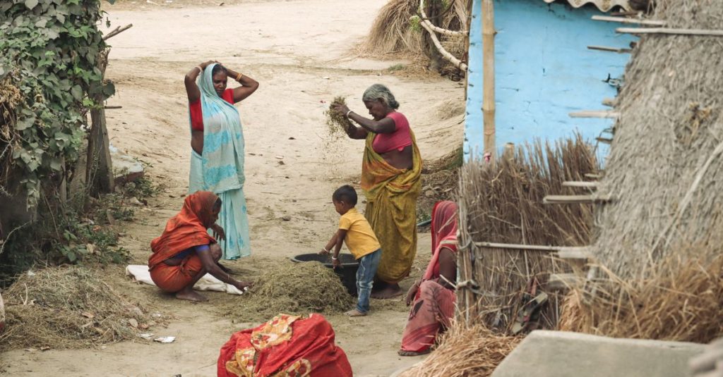 Kehidupan pedesaan tradisional di sebuah desa India yang menunjukkan wanita dan seorang anak yang terlibat dalam pekerjaan pertanian.