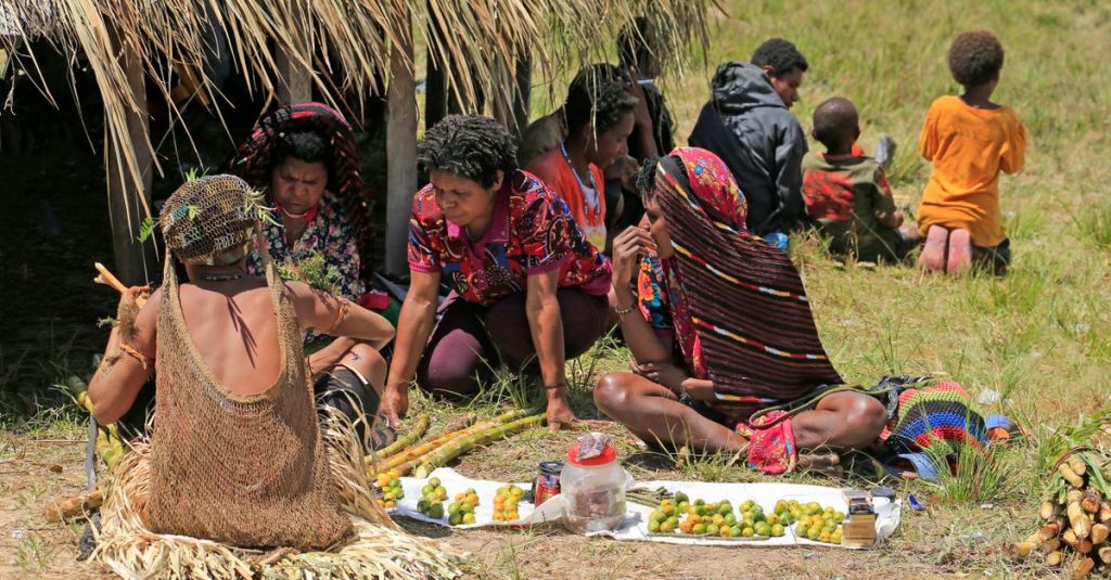 Sekelompok orang berbagi buah di pasar luar ruangan pedesaan, sebuah pertukaran budaya tradisi.