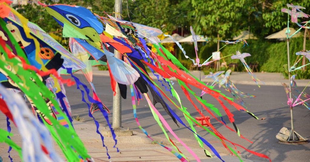 Layang-layang berwarna cerah dengan ekor yang berkilauan dipajang di luar ruangan pada hari yang cerah.