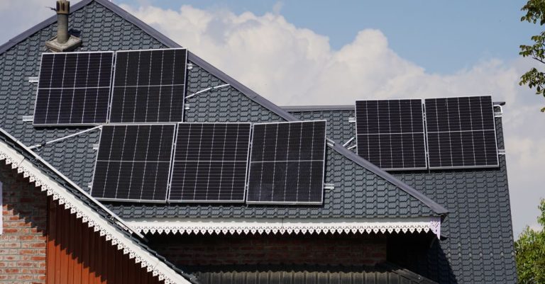 Panel surya di atap sebuah rumah di Srinagar dengan latar belakang langit biru.