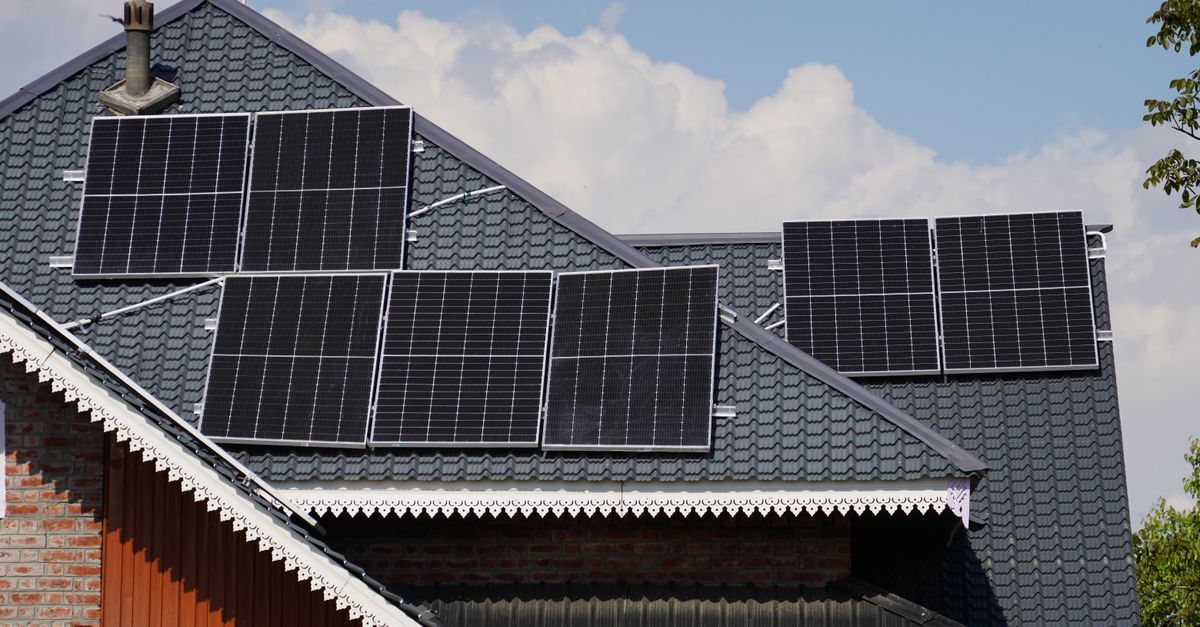 Panel surya di atap sebuah rumah di Srinagar dengan latar belakang langit biru.