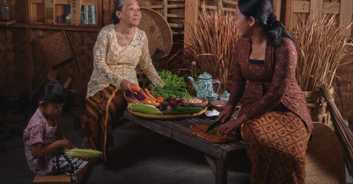 Tiga generasi berkumpul untuk memasak tradisional di dapur Jawa yang rustik.