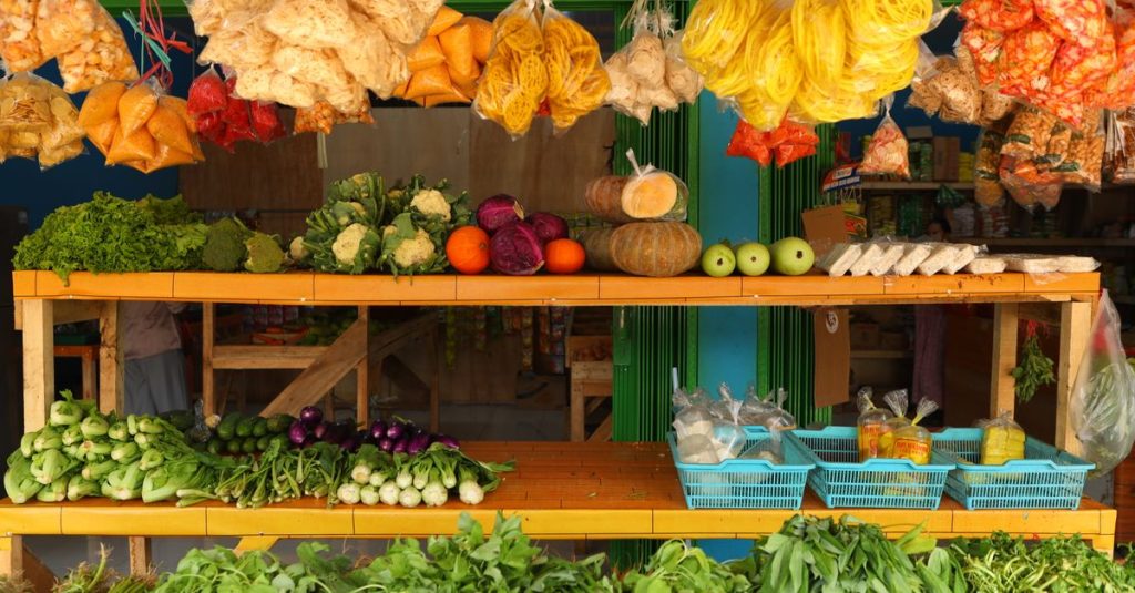 Gerai pasar berwarna-warni di Jawa Barat yang menampilkan berbagai sayuran segar dan camilan tradisional.