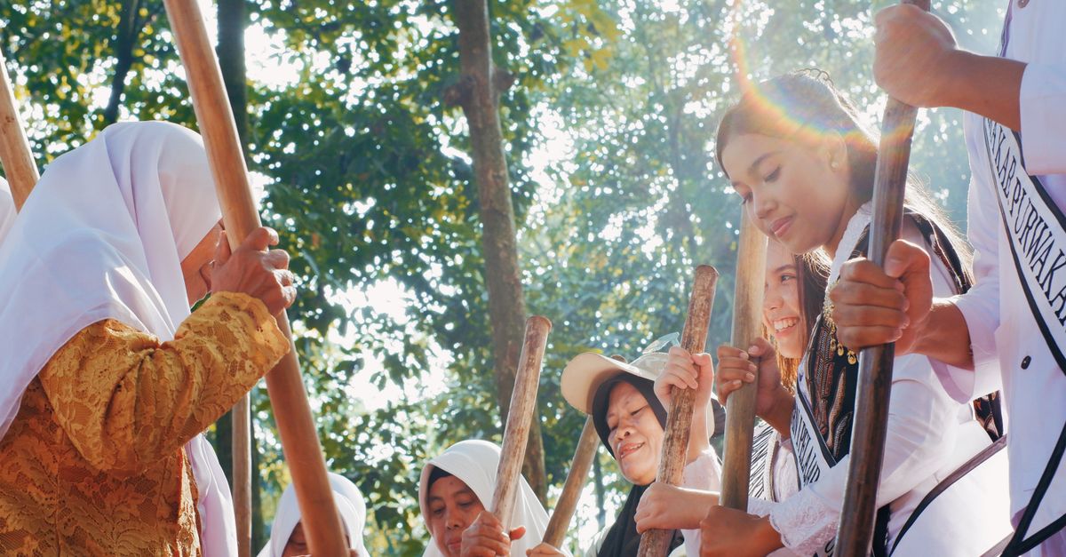 Perempuan berpakaian tradisional berpartisipasi dalam tari di Jawa Barat, Indonesia, di bawah sinar matahari.