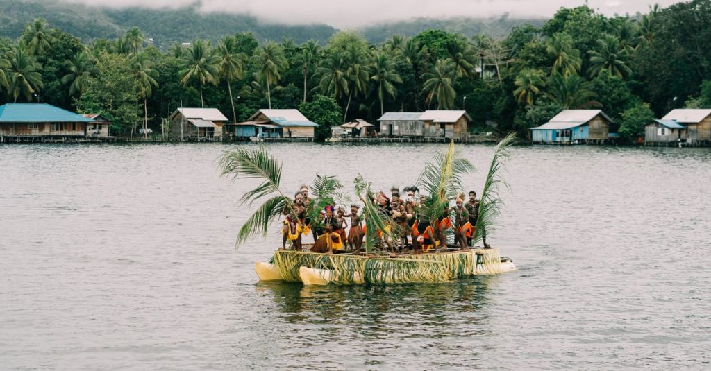 Sekelompok orang berada di atas perahu tradisional di sebuah danau yang tenang di Papua, Indonesia.