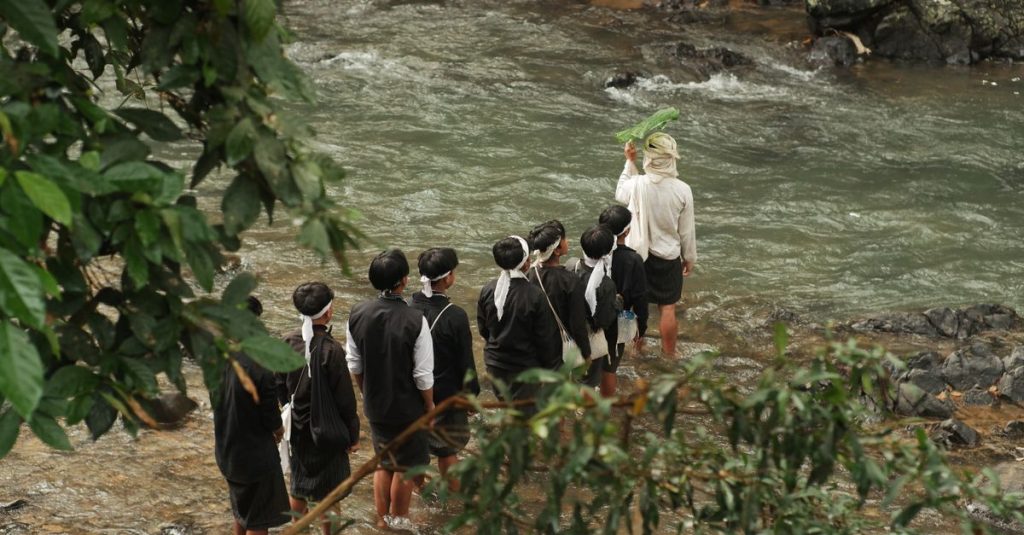 Ritual budaya di tepi sungai di Banten, Indonesia, yang menampilkan pakaian tradisional dan pertemuan komunitas.