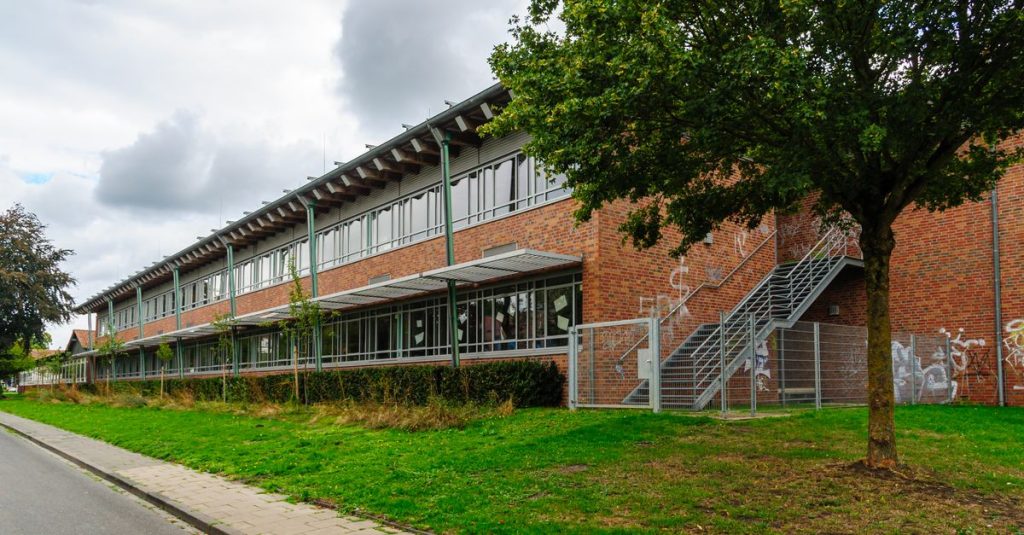 Gedung sekolah modern dengan fasad bata dan tanaman hijau di Coesfeld, Jerman.