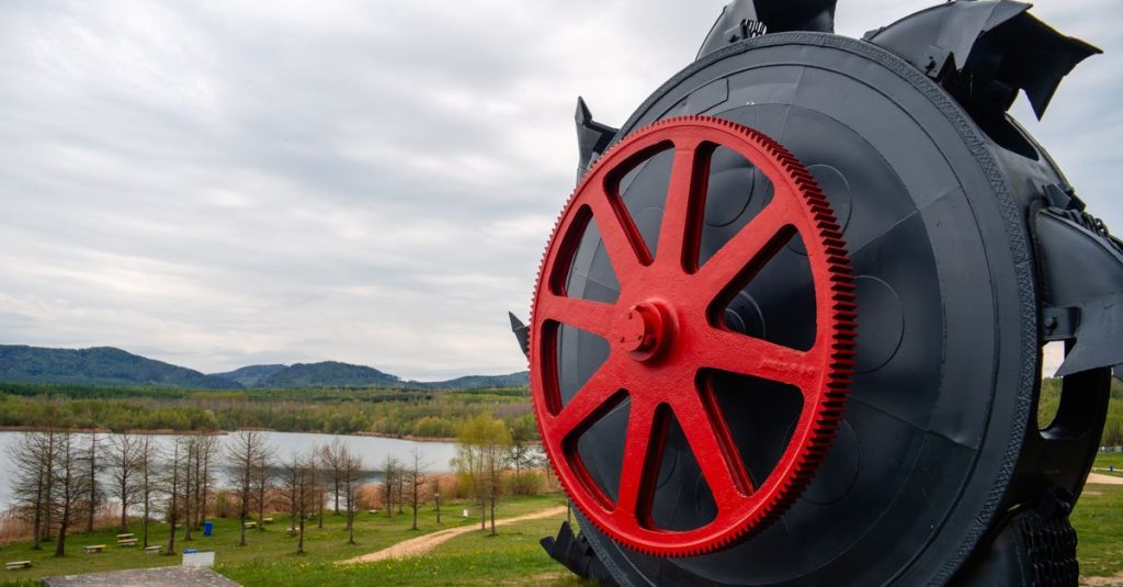 Sebuah patung roda industri yang mencolok dengan latar belakang pemandangan indah Olbersdorf, Sachsen.