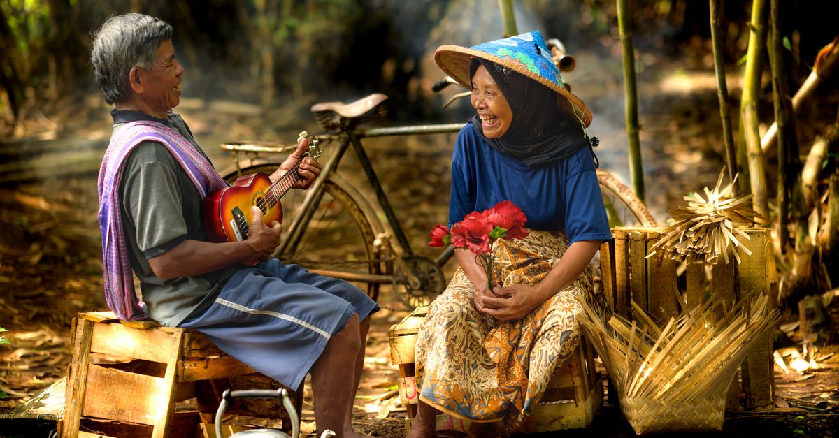 Pemandangan menawan pasangan lansia yang berbagi musik dan tawa di Jakarta, Indonesia.