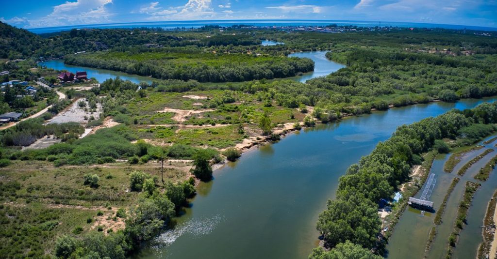 Pemandangan udara dari hijauan subur dan sungai yang berkelok di Prachuap Khiri Khan, Thailand di bawah langit biru yang cerah.
