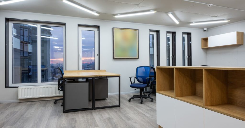 Ruang kantor yang luas dan modern dengan jendela besar dan perabot minimalis.