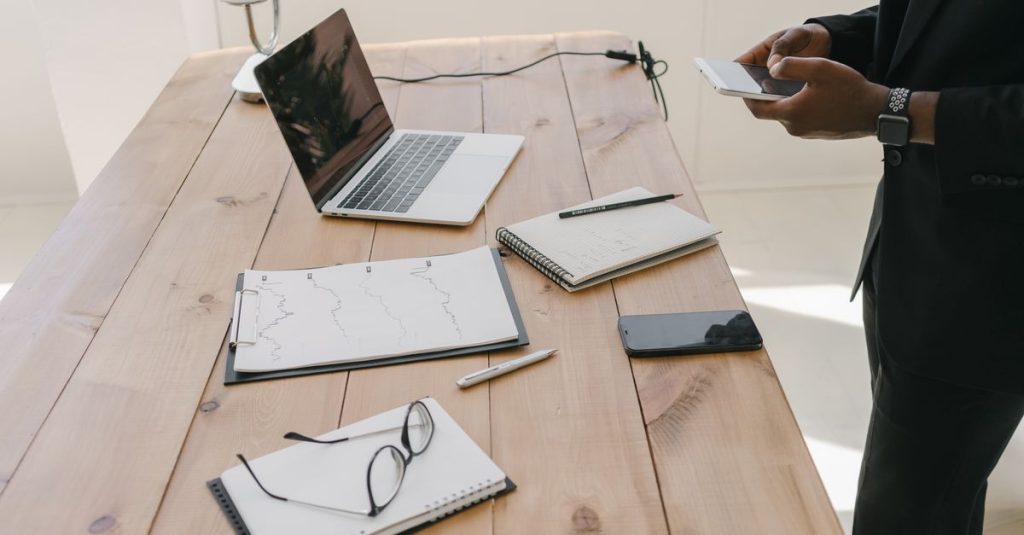 Pengaturan kantor modern yang menampilkan laptop, dokumen, dan alat tulis di atas meja kayu.