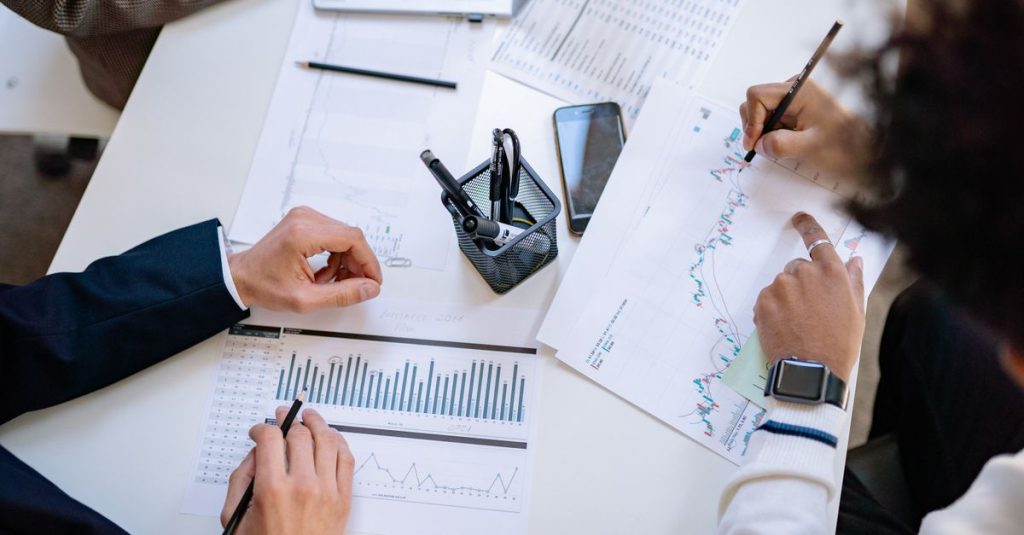 Tim bisnis menganalisis grafik dan diagram keuangan selama pertemuan kolaboratif.