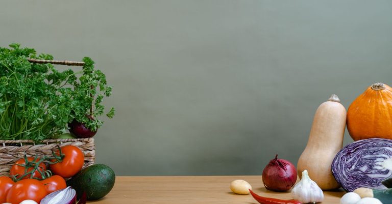 Sayuran organik segar yang bervariasi termasuk tomat, bawang putih, dan labu di atas meja kayu.