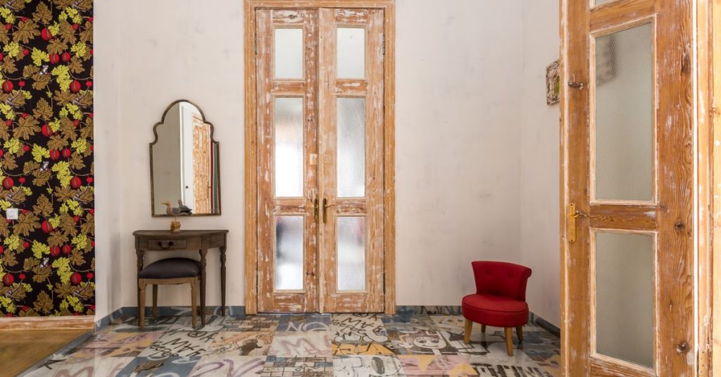 Ruang vintage yang menawan dengan pintu kayu yang terdistorsi dan lantai bermotif grafis.