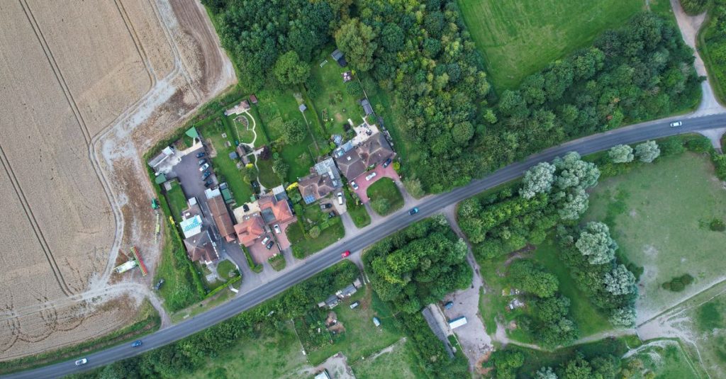 Pemandangan udara dron Barton-le-Clay, Inggris yang menampilkan jalan, ladang, dan rumah.