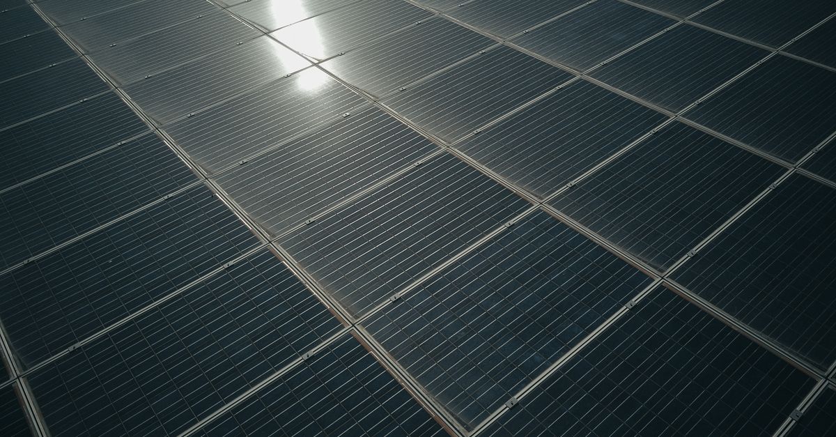 Close-up menawan panel surya yang memantulkan sinar matahari, menampilkan teknologi energi terbarukan.