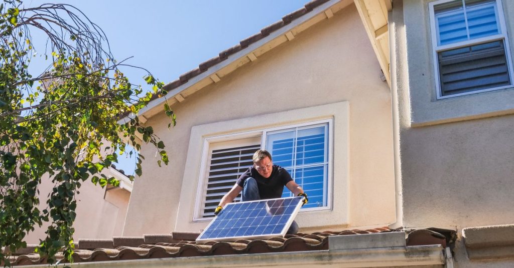 Teknisi solar memasang panel fotovoltaik di atap yang cerah.